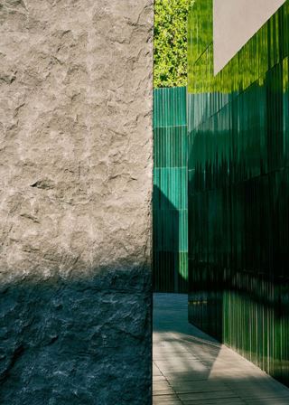 Luxury area decorated with green lava stone tiles and a rough stone wall.