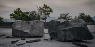 Due grandi blocchi di pietra lavica grezza su una superficie esterna, con alberi sullo sfondo.