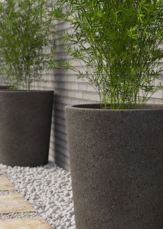 Lava stone plant pots in dark color, arranged on a white gravel surface.